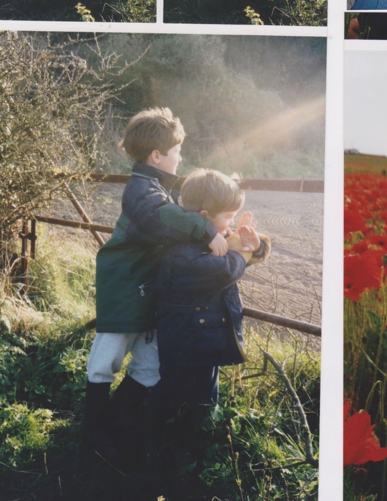 Two young brothers at a field gate, one with his arm around the other