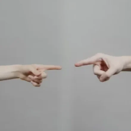 How to choose a coach: two hands pointing towards each other across an empty grey space